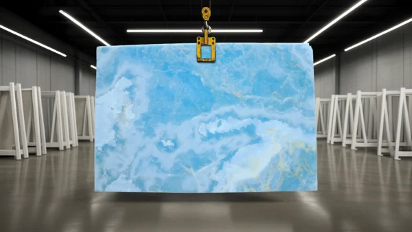 Blue marble slab suspended by a yellow hoist hook in a warehouse environment